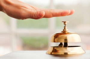 Hand ringing brass bell on hotel reception desk